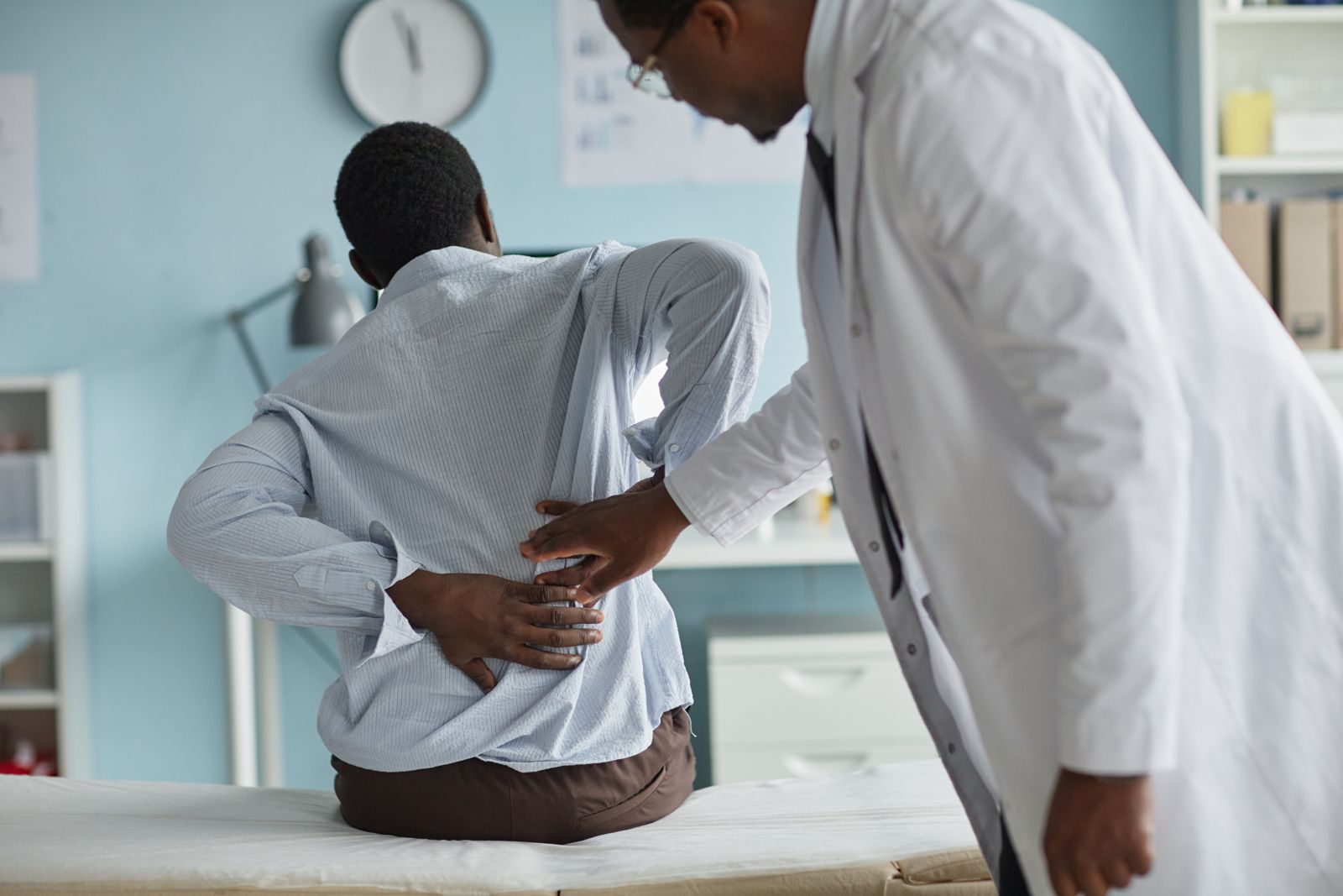 A physician examining a patient's lower back.
