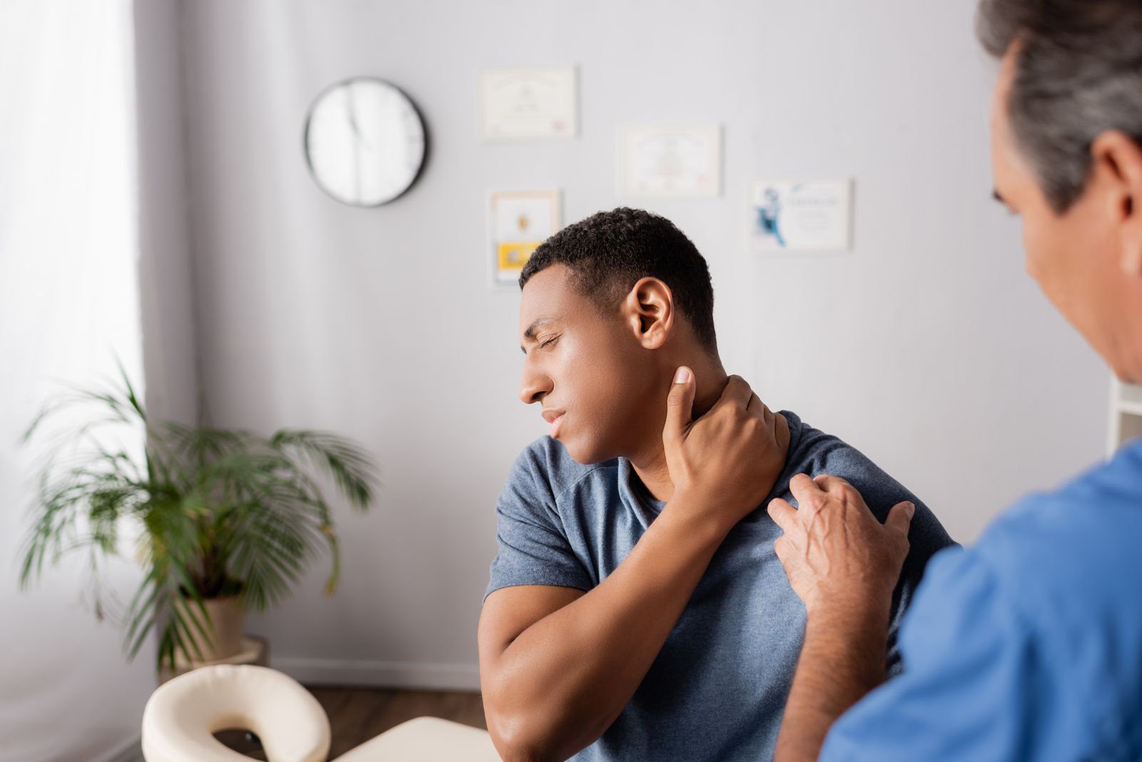 A patient holding his neck while talking with a clinician.