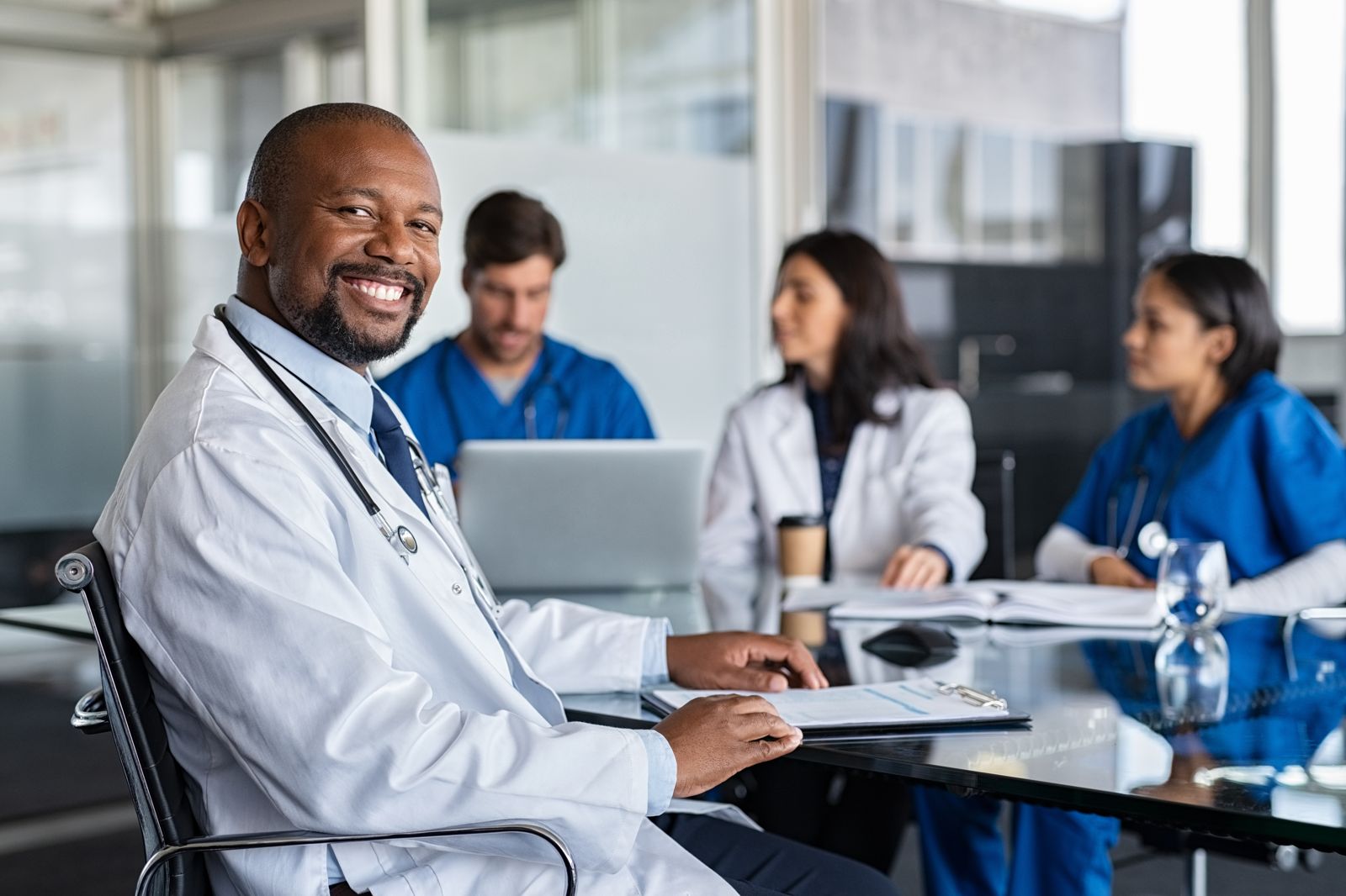 A smiling physician meeting with his care team.