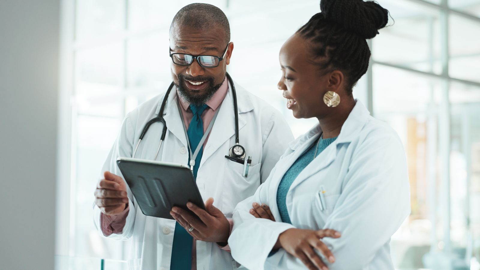 Two physicians reviewing a tablet together.