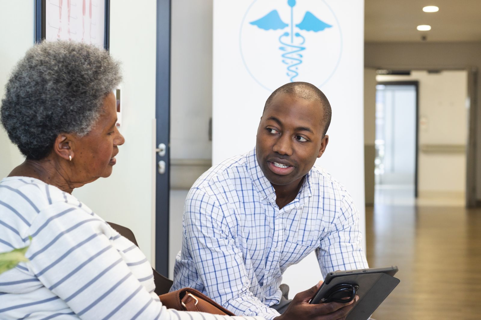 A clinician helping an older patient on a tablet in the waiting room.